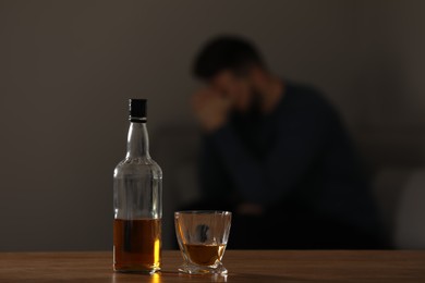 Photo of Addicted man at home, focus on table with alcoholic drink. Space for text