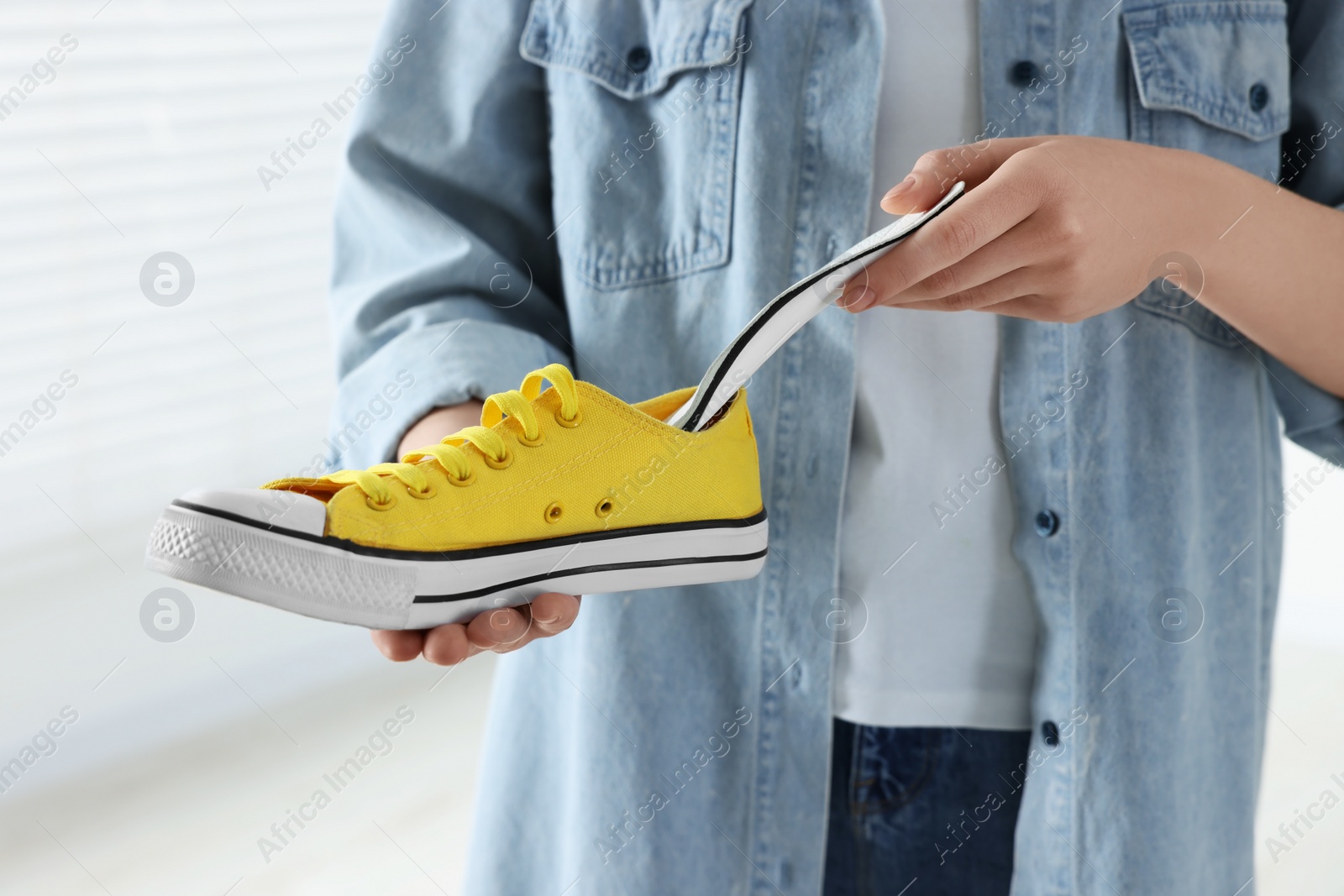 Photo of Woman putting orthopedic insole into shoe indoors, closeup. Foot care