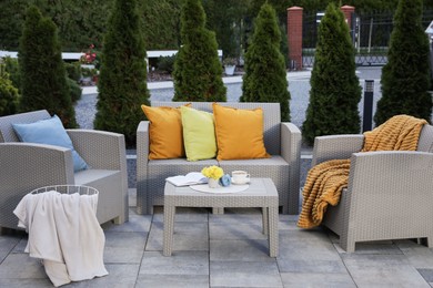 Beautiful rattan garden furniture, soft pillows and different decor elements outdoors