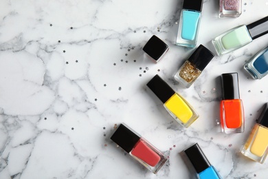 Photo of Bottles of nail polish on marble background, top view with space for text