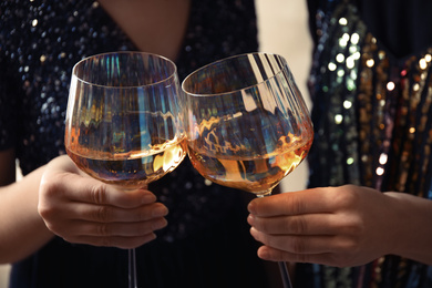 Photo of Women clinking glasses with white wine, closeup