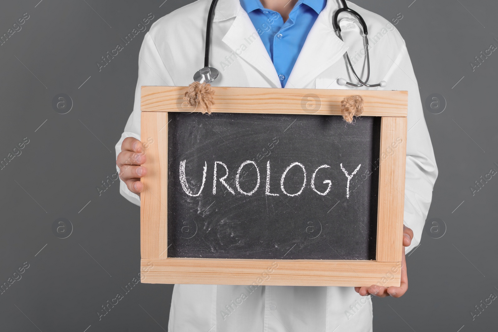 Photo of Male doctor holding chalkboard with word UROLOGY on grey background