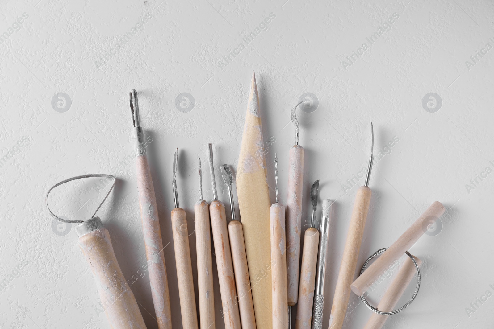 Photo of Set of different clay crafting tools on white table, top view
