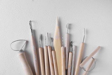 Set of different clay crafting tools on white table, top view