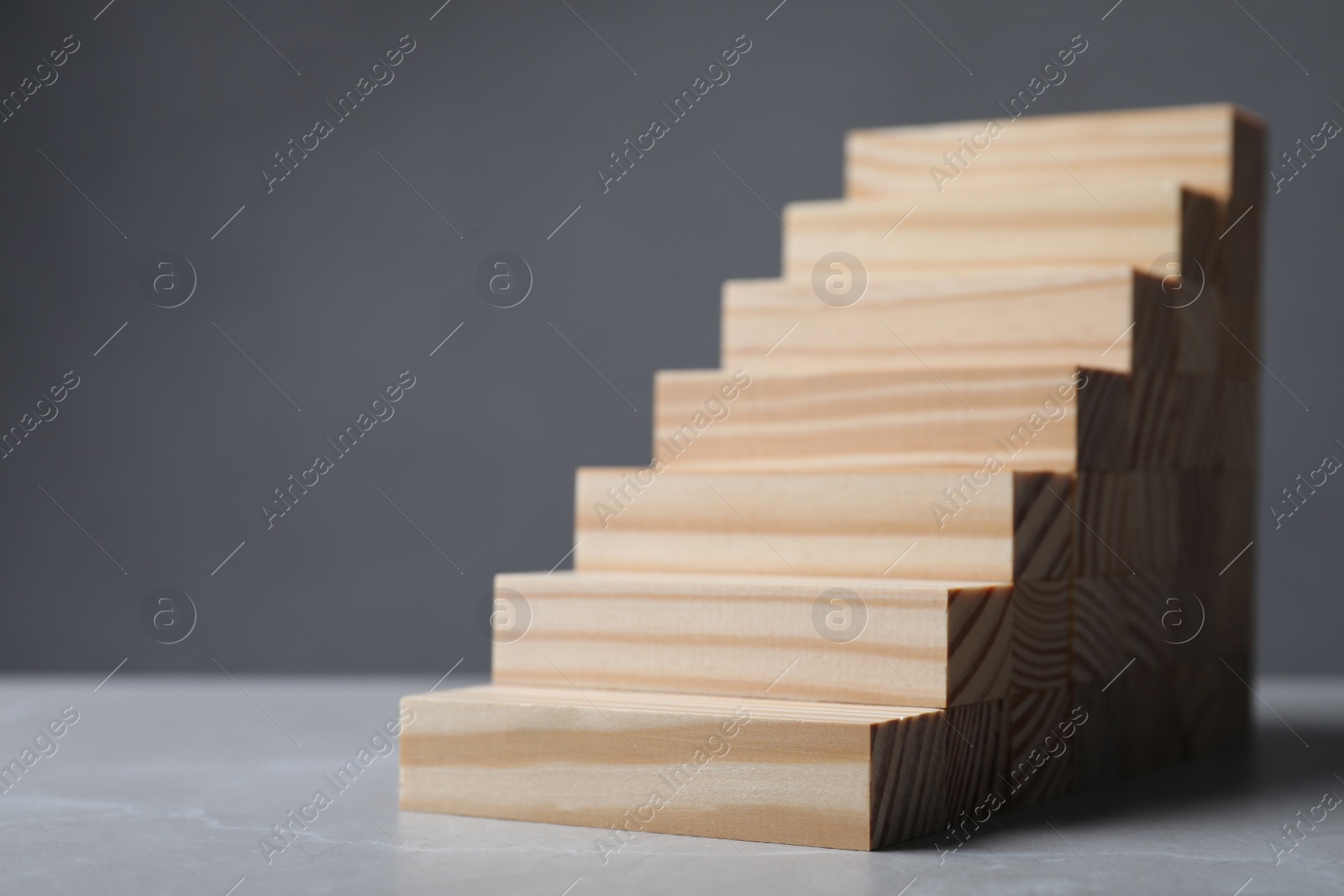 Photo of Steps made with wooden blocks on table against grey background, space for text. Career ladder