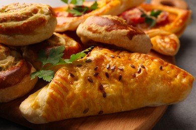 Different delicious puff pastry with tasty filling on wooden board, closeup