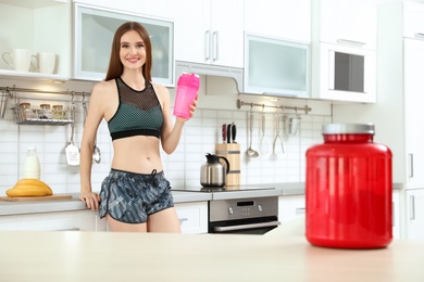 Photo of Young woman with bottle of protein shake in kitchen