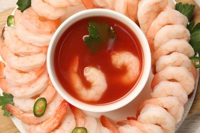 Photo of Tasty boiled shrimps with cocktail sauce, chili and parsley on wooden table, top view