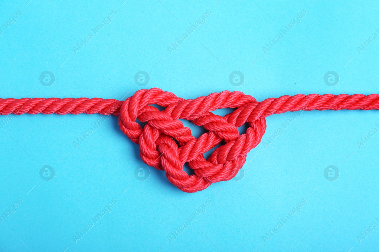 Photo of Heart made of red rope on color background, top view