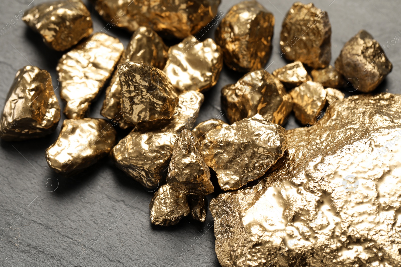 Photo of Pile of gold nuggets on black table, closeup
