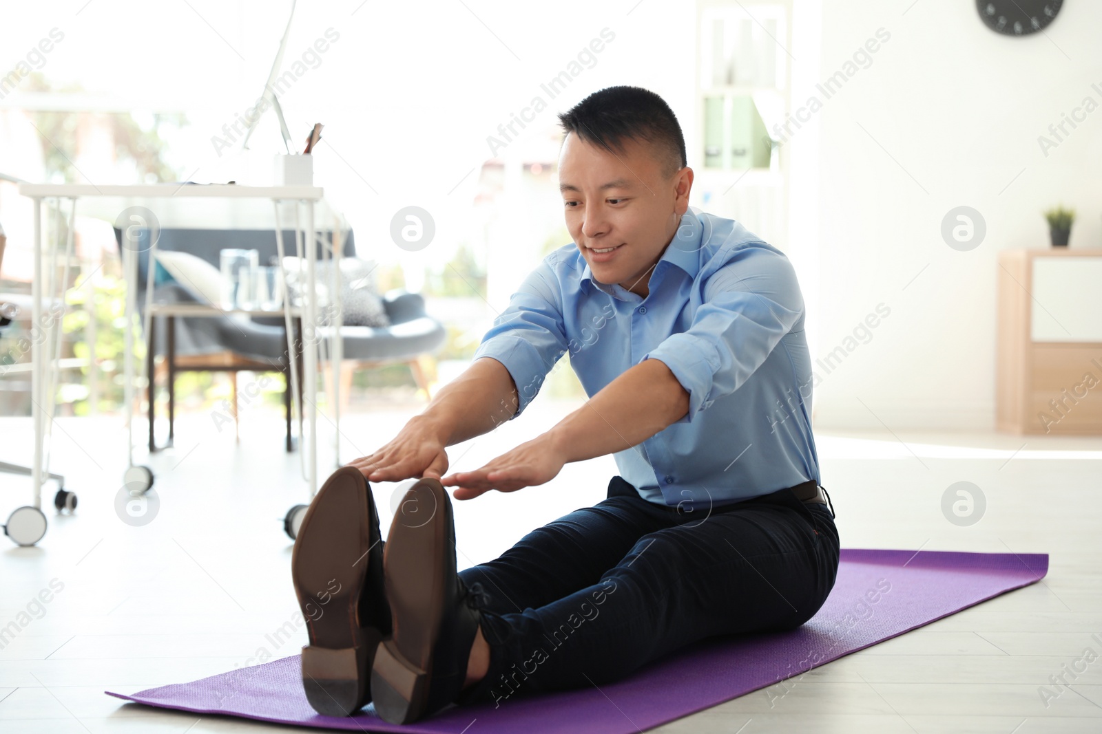 Photo of Young businessman stretching in office. Workplace fitness