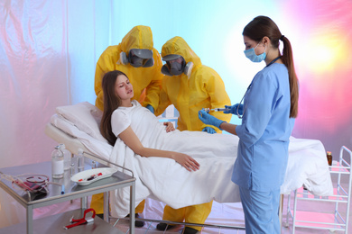 Professional paramedics examining patient with virus in quarantine ward