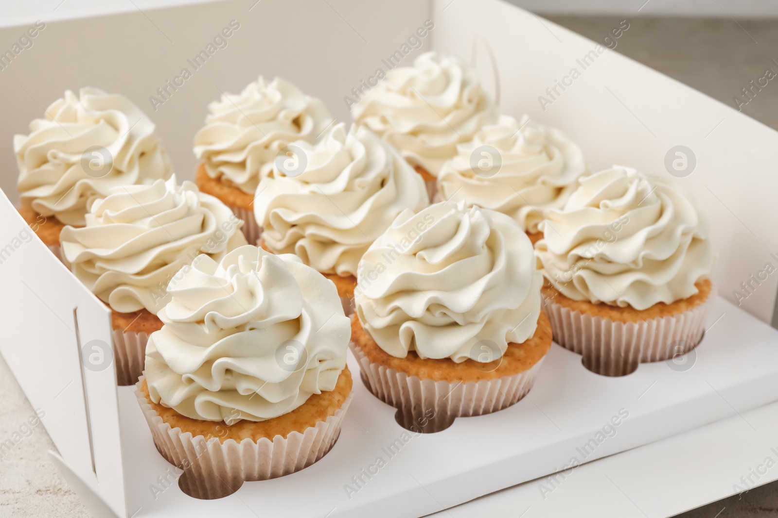 Photo of Tasty cupcakes with vanilla cream in box, closeup