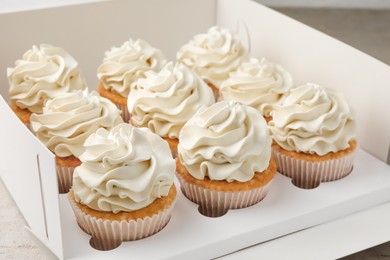 Photo of Tasty cupcakes with vanilla cream in box, closeup