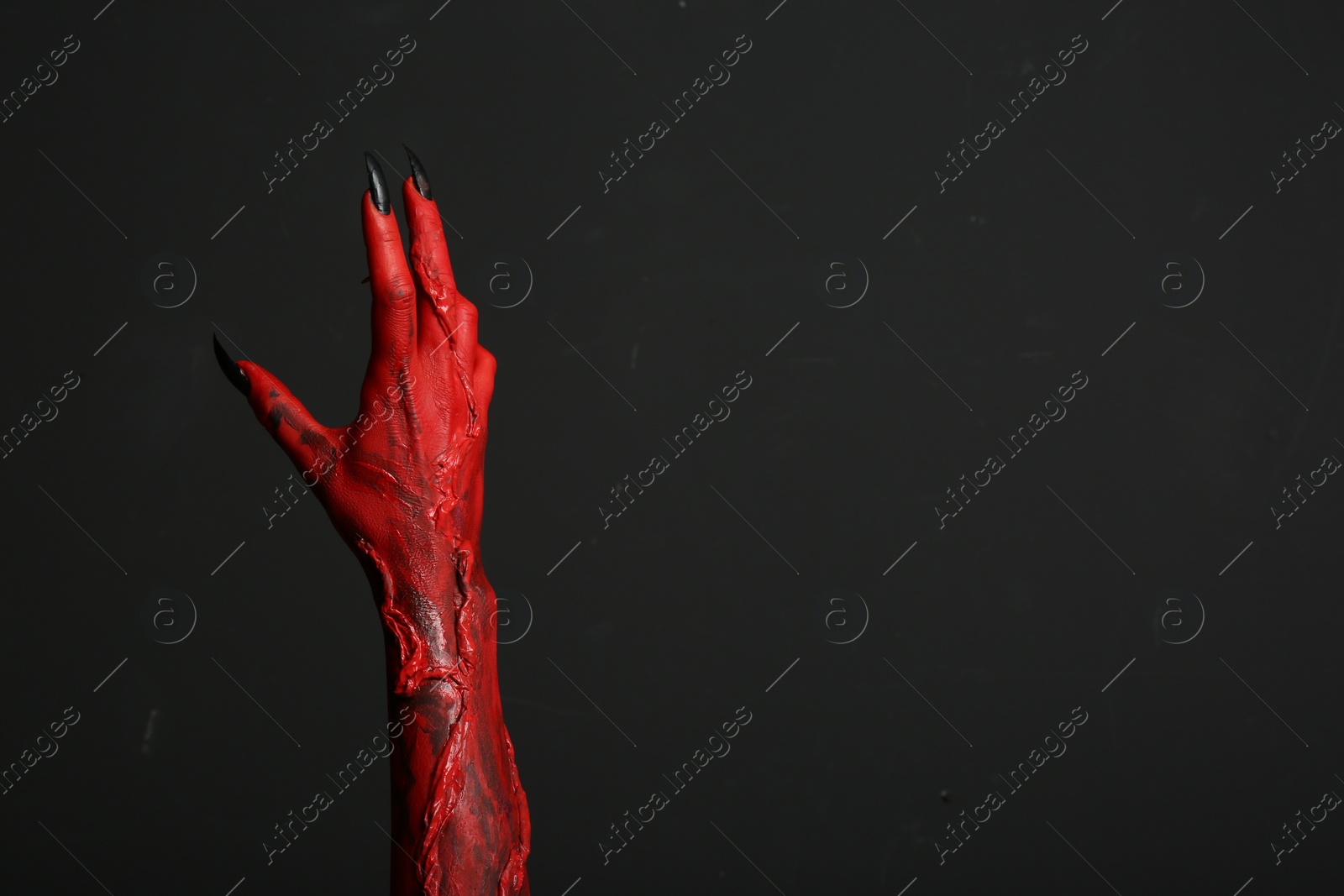 Photo of Scary monster on black background, closeup of hand with space for text. Halloween character