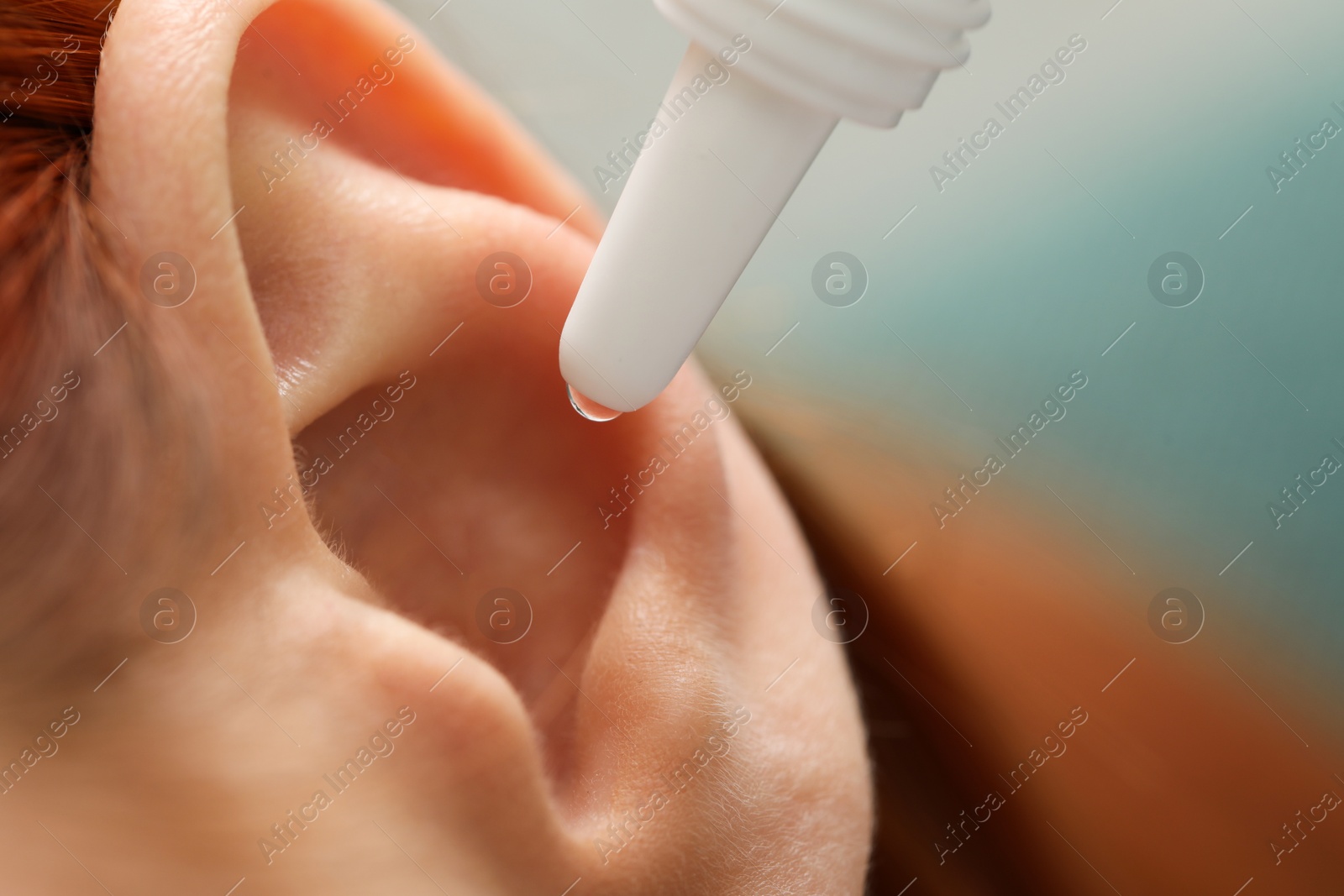 Photo of Woman applying medical ear drops, macro view