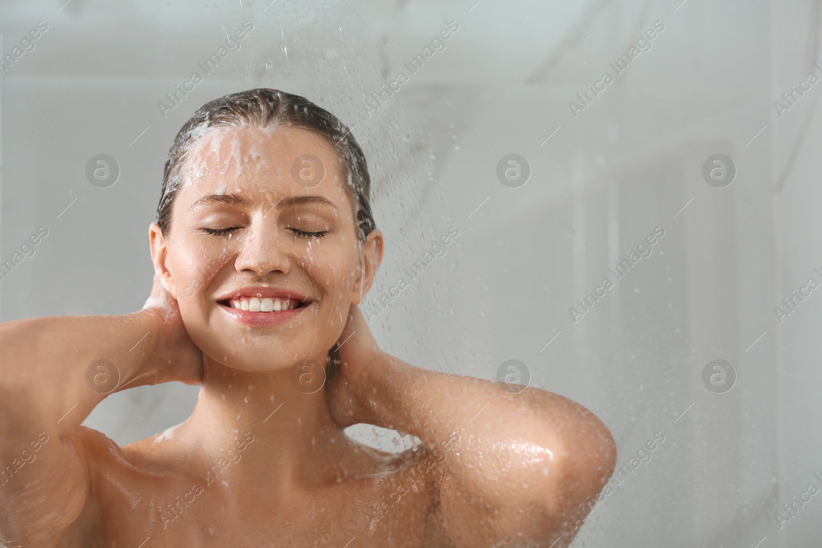 Image of Beautiful young woman washing hair in shower at home. Space for text