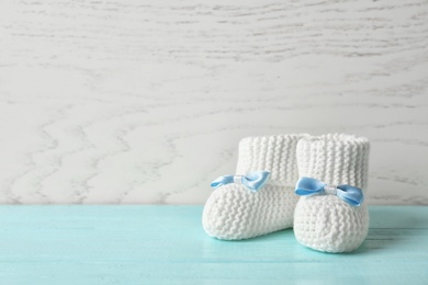 Handmade baby booties on table against wooden background. Space for text