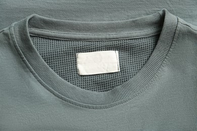 Photo of Blank clothing label on grey sweater, top view