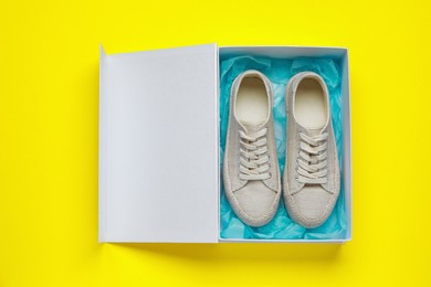 Comfortable shoes in cardboard box on yellow background, top view