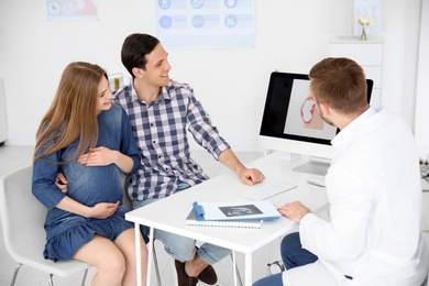 Photo of Gynecology consultation. Future parents with doctor in hospital