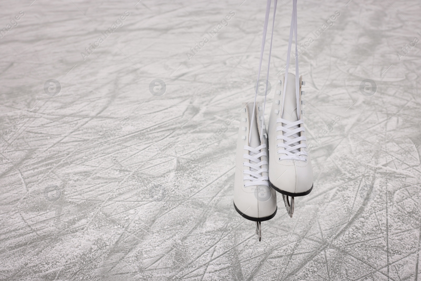 Photo of Pair of figure skates hanging over ice, space for text