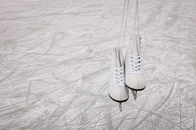 Pair of figure skates hanging over ice, space for text