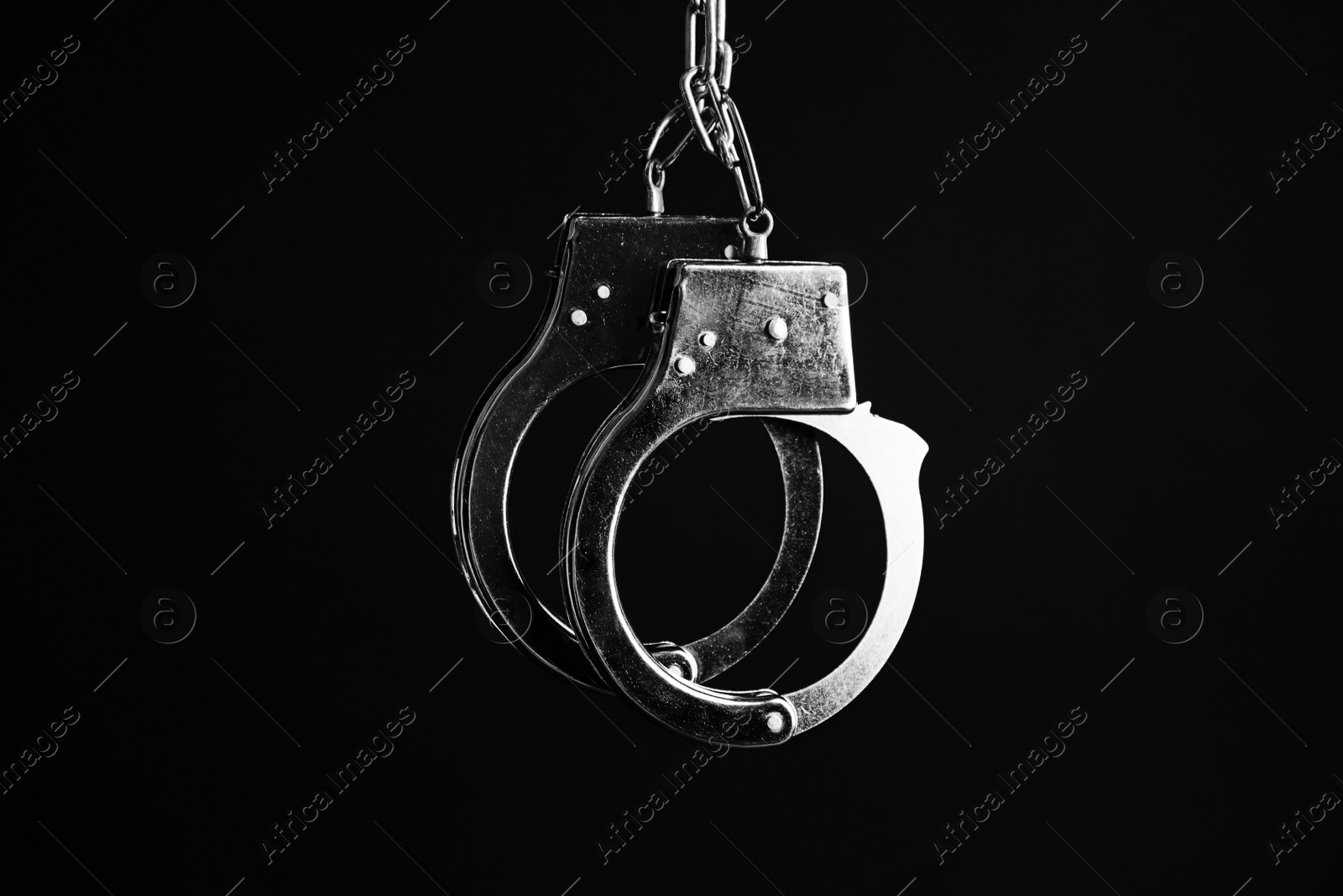 Photo of Classic chain handcuffs hanging on black background