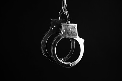 Photo of Classic chain handcuffs hanging on black background