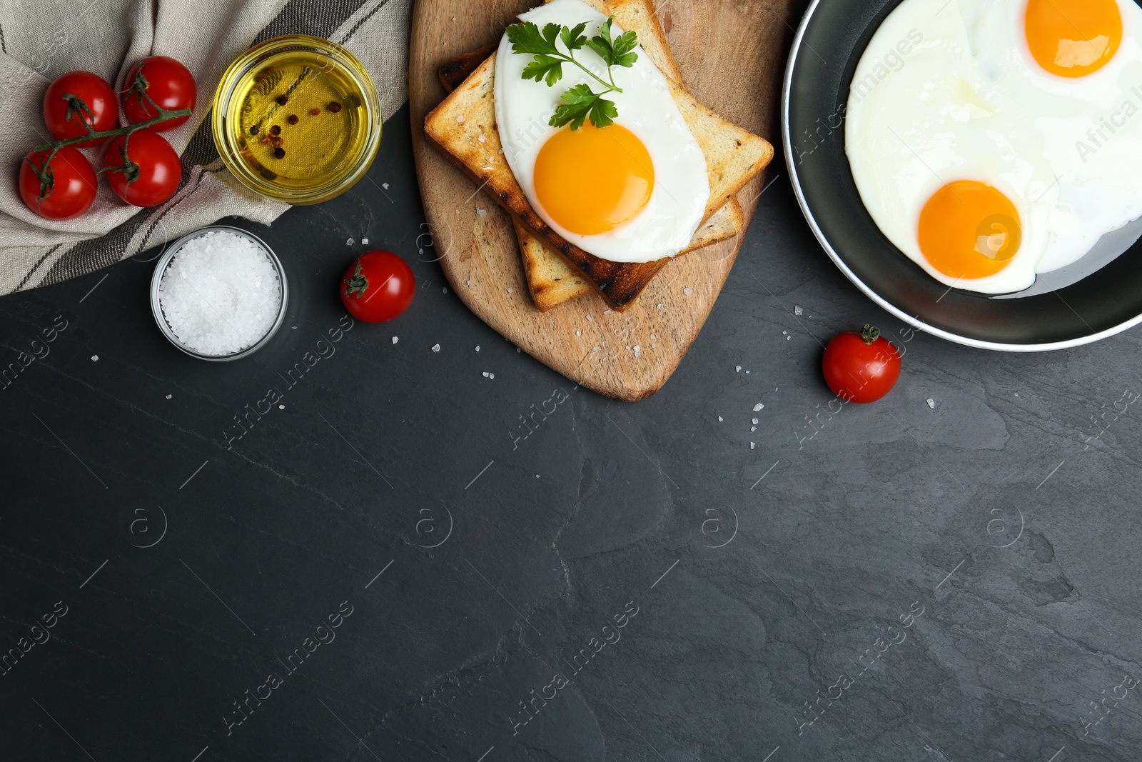 Photo of Flat lay composition with tasty fried eggs on black table. Space for text