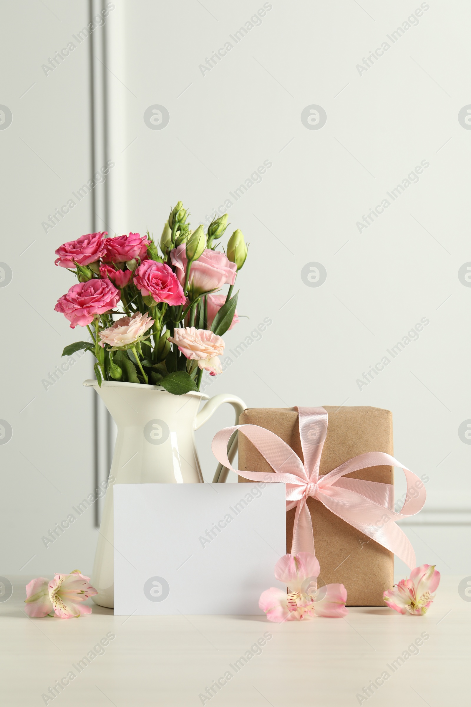 Photo of Happy Mother's Day. Gift box, blank card and beautiful flowers on white table