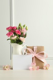 Photo of Happy Mother's Day. Gift box, blank card and beautiful flowers on white table