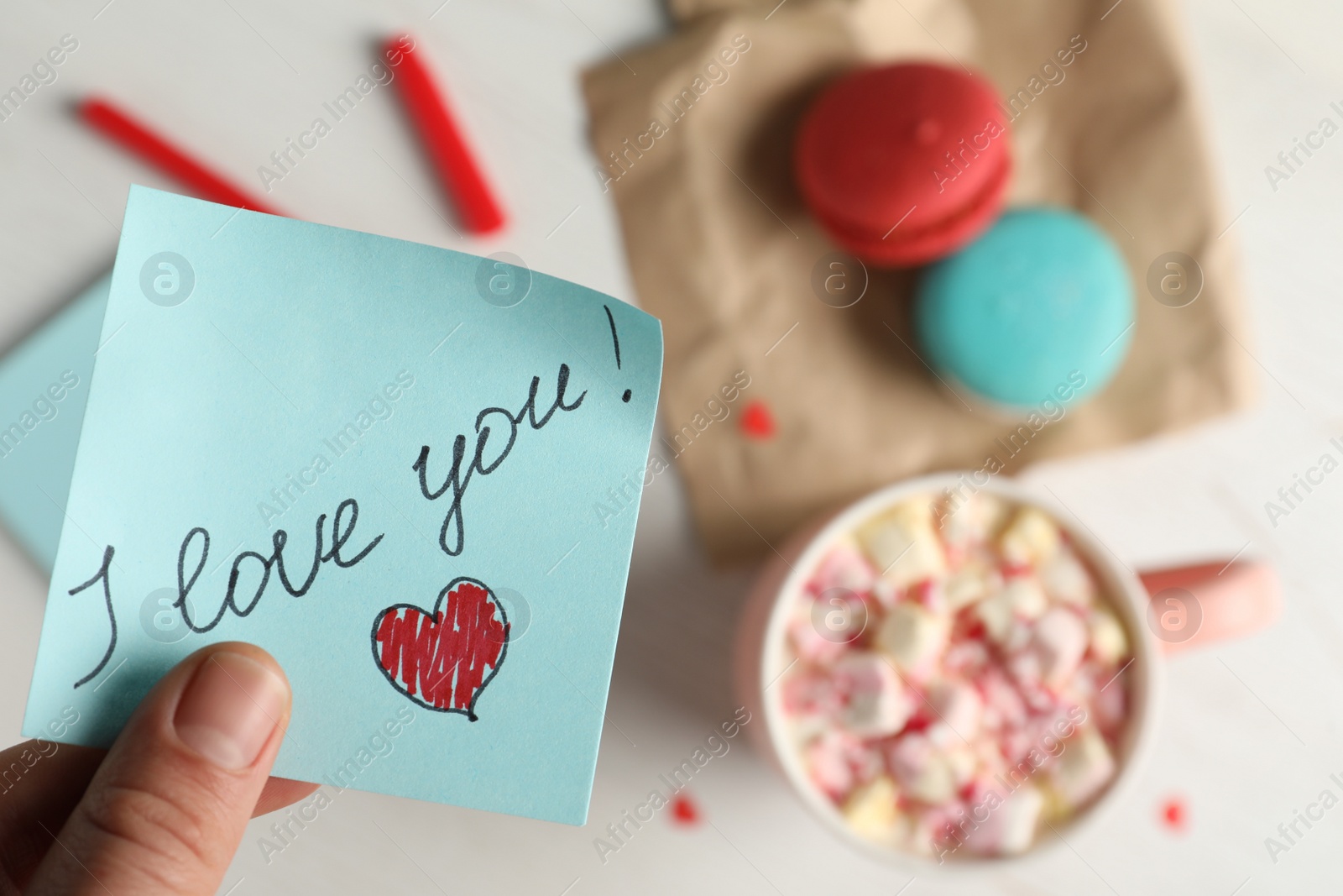 Photo of Woman holding blue note with phrase I Love You, closeup