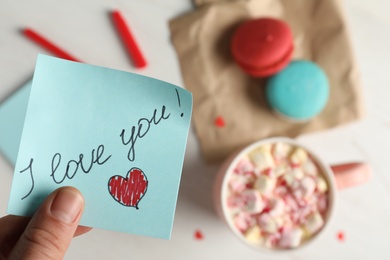 Woman holding blue note with phrase I Love You, closeup