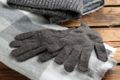 Stylish gloves, scarf and hat on wooden background, closeup
