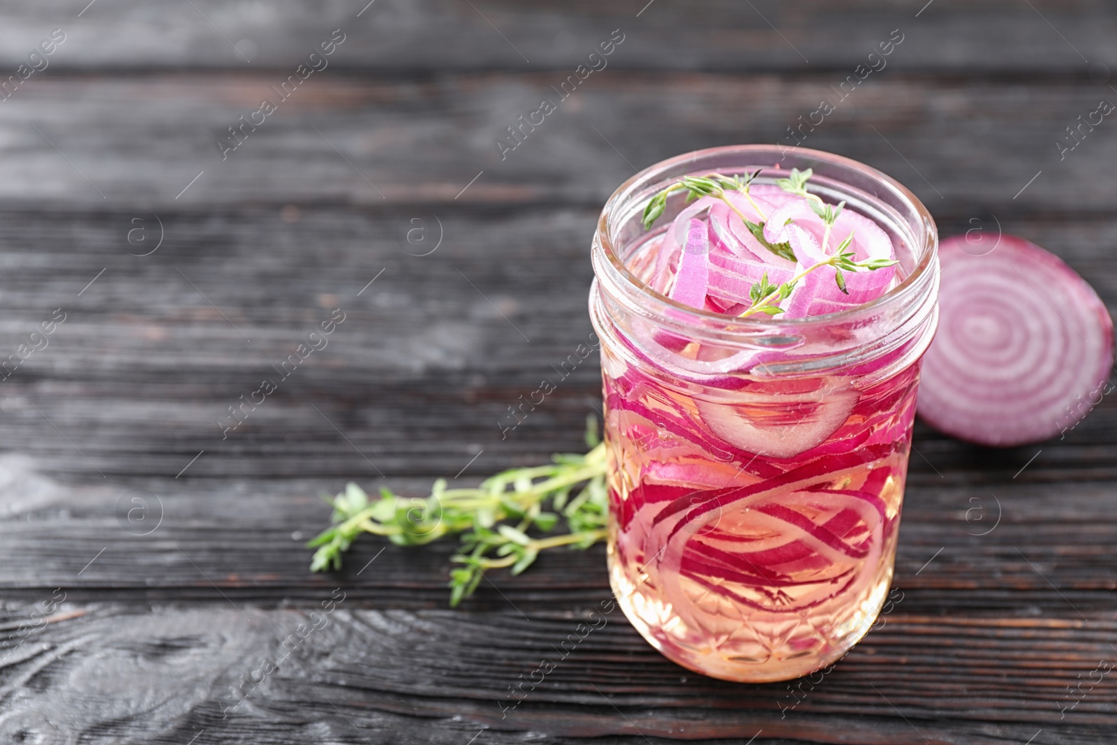 Photo of Jar of pickled onions on wooden table. Space for text