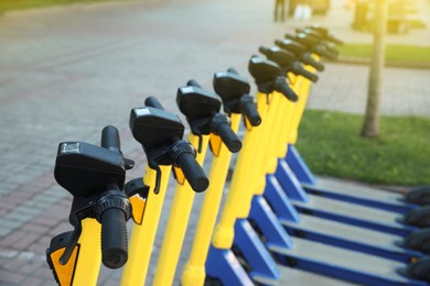 Many modern electric scooters on city street, closeup. Rental service