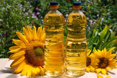 Photo of Bottles of sunflower oil on wooden table outdoors