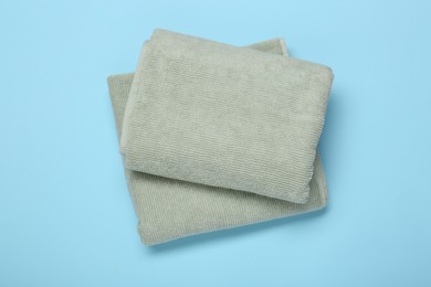Folded terry towels on light blue background, top view