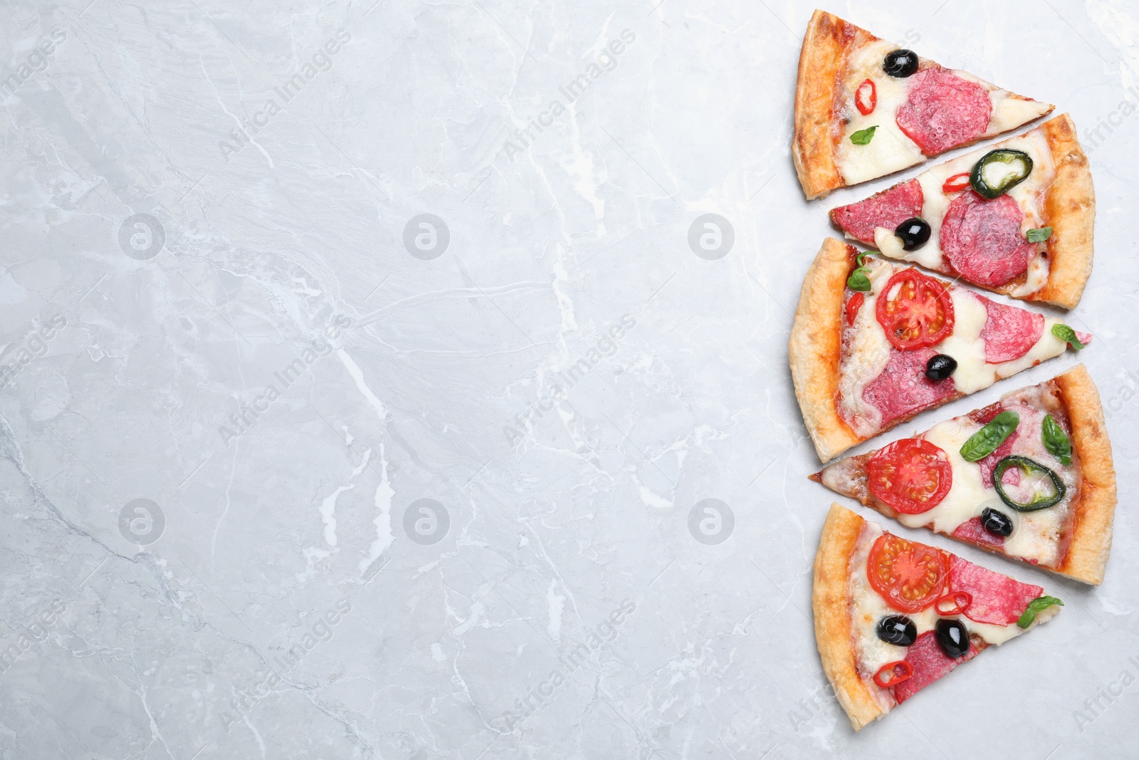 Photo of Pieces of delicious pizza Diablo on light marble background, flat lay. Space for text