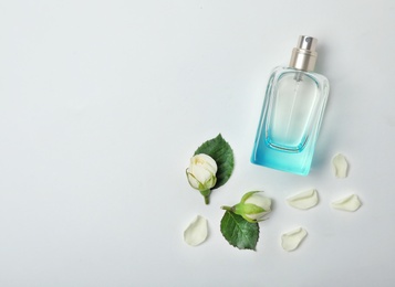 Transparent bottle of perfume with beautiful roses on white background