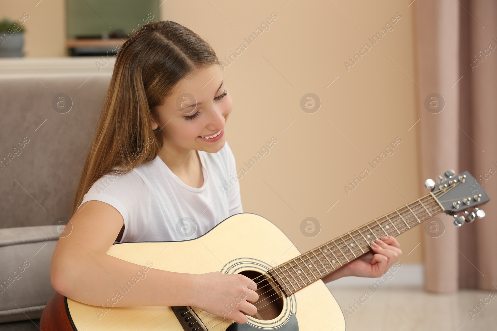 Photo of Teenage girl playing acoustic guitar in room