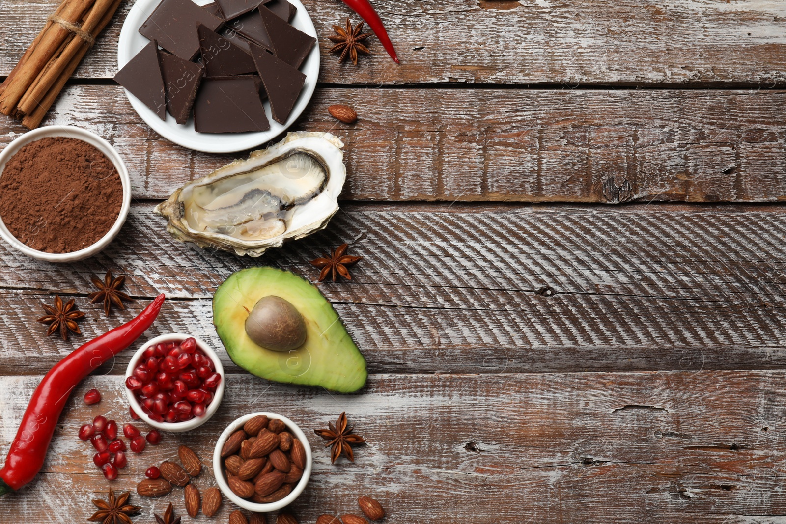 Photo of Natural aphrodisiac. Different food products and heart model on wooden table, flat lay. Space for text