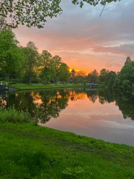 Picturesque view of pond and green grass at sunset