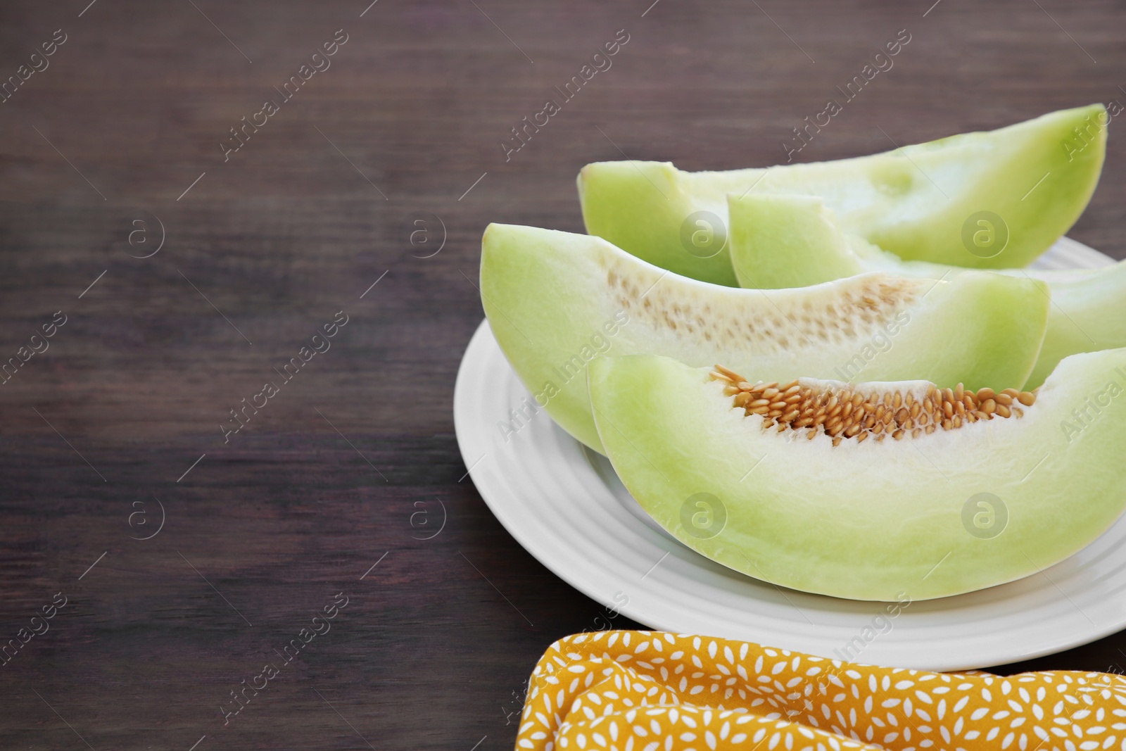 Photo of Cut tasty ripe melon on wooden table. Space for text