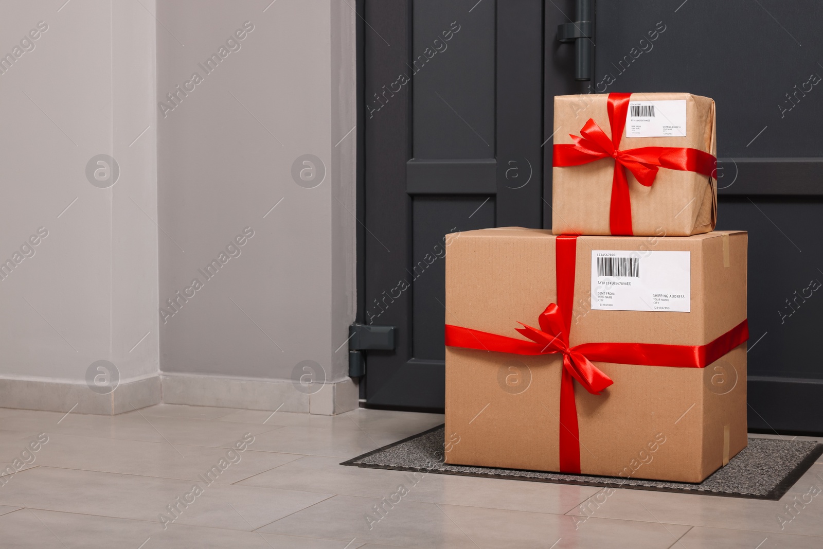 Photo of Christmas gift boxes on floor near door, space for text. Sending present by mail