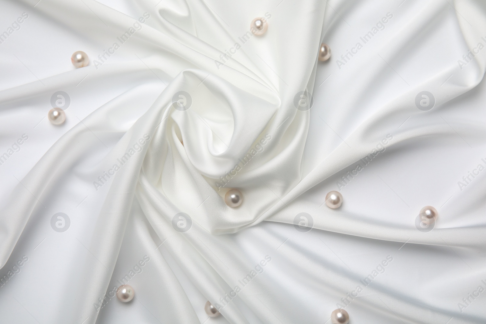 Photo of Beautiful pearls on white silk, flat lay