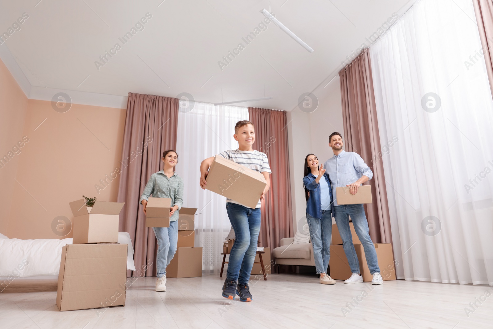 Photo of Happy family with moving boxes in apartment. Settling into new house