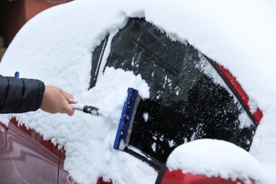 Man cleaning snow from car outdoors on winter day, closeup. Frosty weather