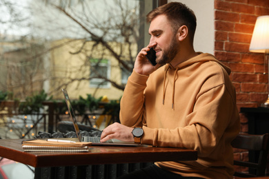 Male blogger talking on phone in cafe